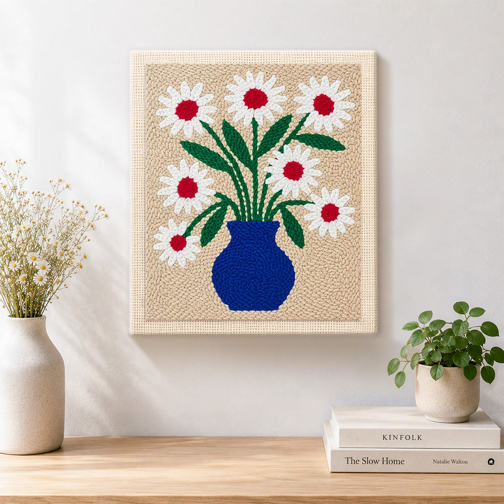 Finished blue vase with red-centred daisies artwork displayed on a wall