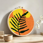 Bold black and yellow leaf punch needle artwork displayed on a table