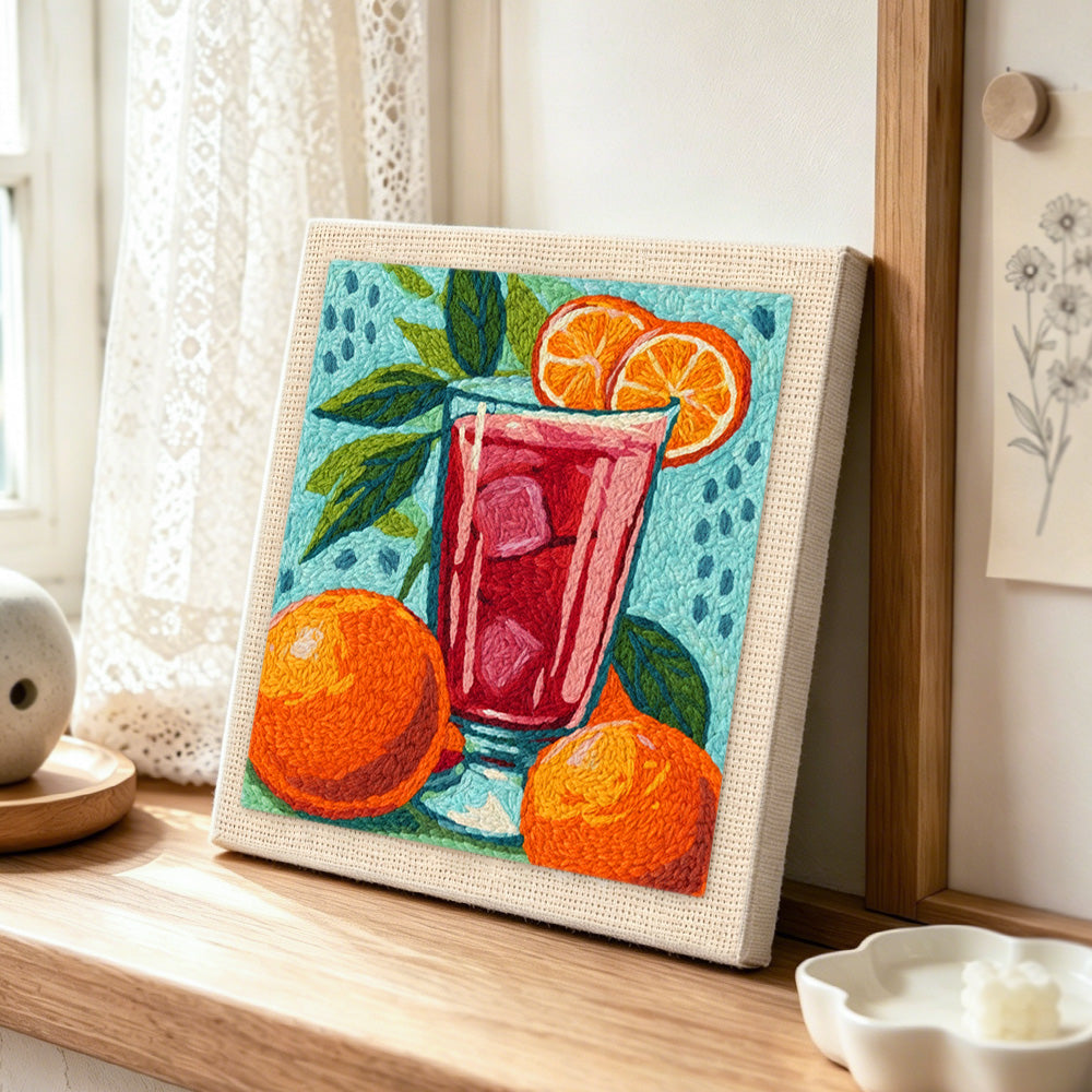 Bold red drink with oranges punch needle artwork displayed on a table