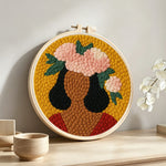 Bold woman with pink floral crown punch needle artwork displayed on a table