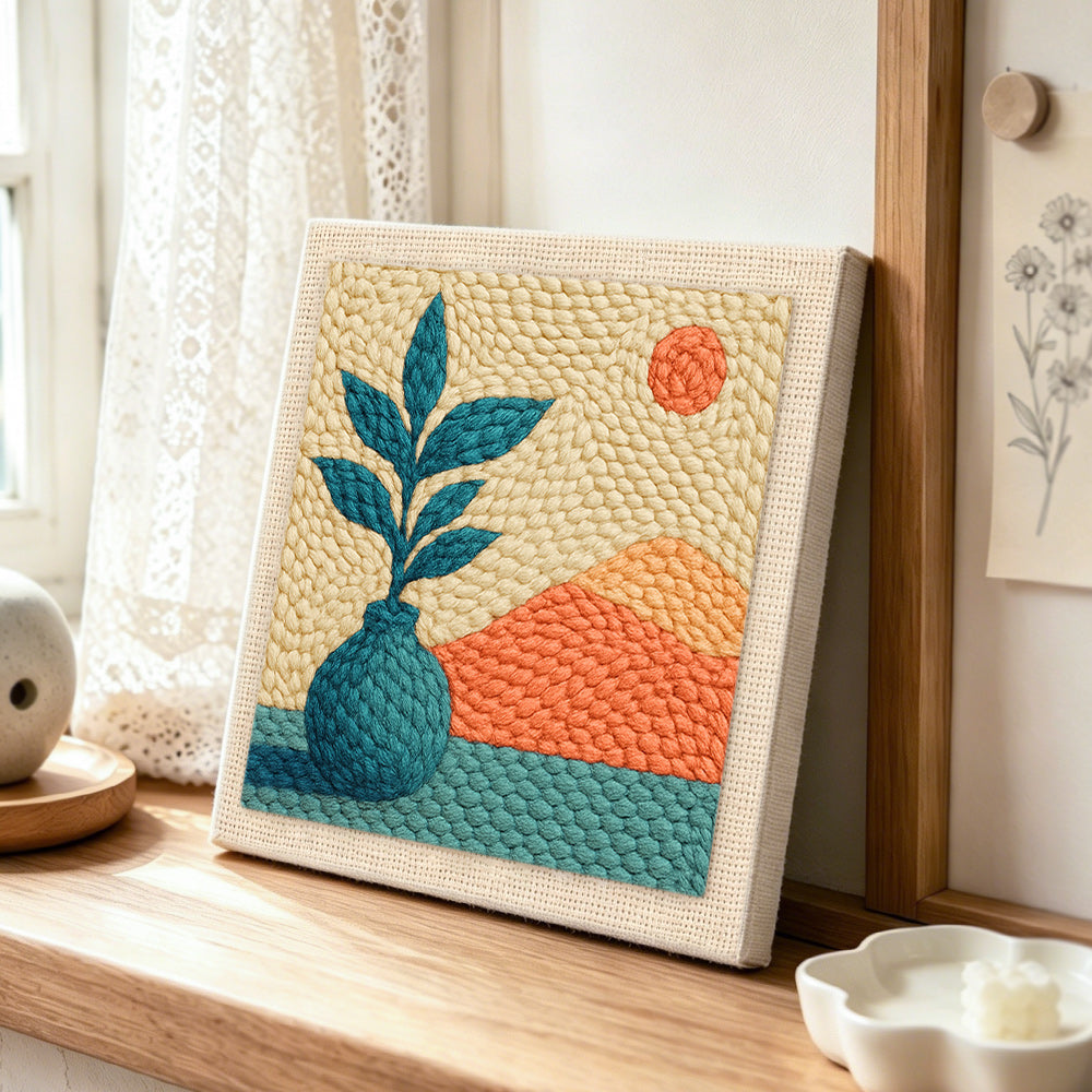 Botanical vase and mountains punch needle artwork displayed on a table