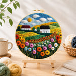Finished bountiful wildflower field and summer cottage needle felting displayed on a wooden easel