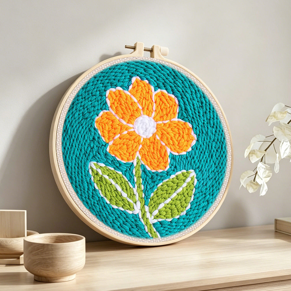 Bright orange flower punch needle artwork displayed on a table