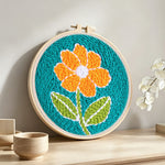 Bright orange flower punch needle artwork displayed on a table