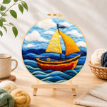 Finished bright yellow sailboat on blue waves needle felting displayed on a wooden easel