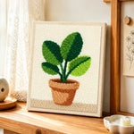 Broad leaf potted plant punch needle artwork displayed on a table