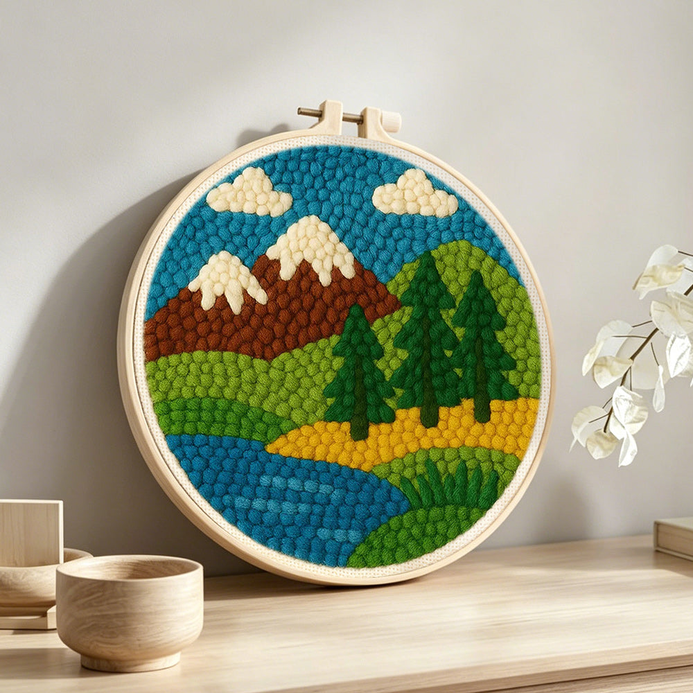 Brown mountains and pine trees by the river punch needle artwork displayed on a table