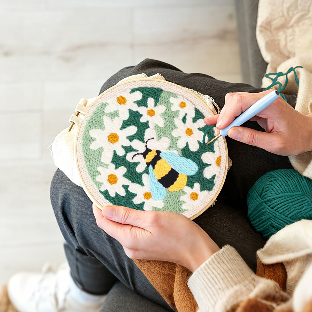 Creating handmade bumblebee among white daisies punch needle artwork
