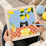 Creating handmade cat peeking at lemon cake punch needle artwork