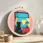 Cat silhouette by window with plants and vases punch needle artwork displayed on a table