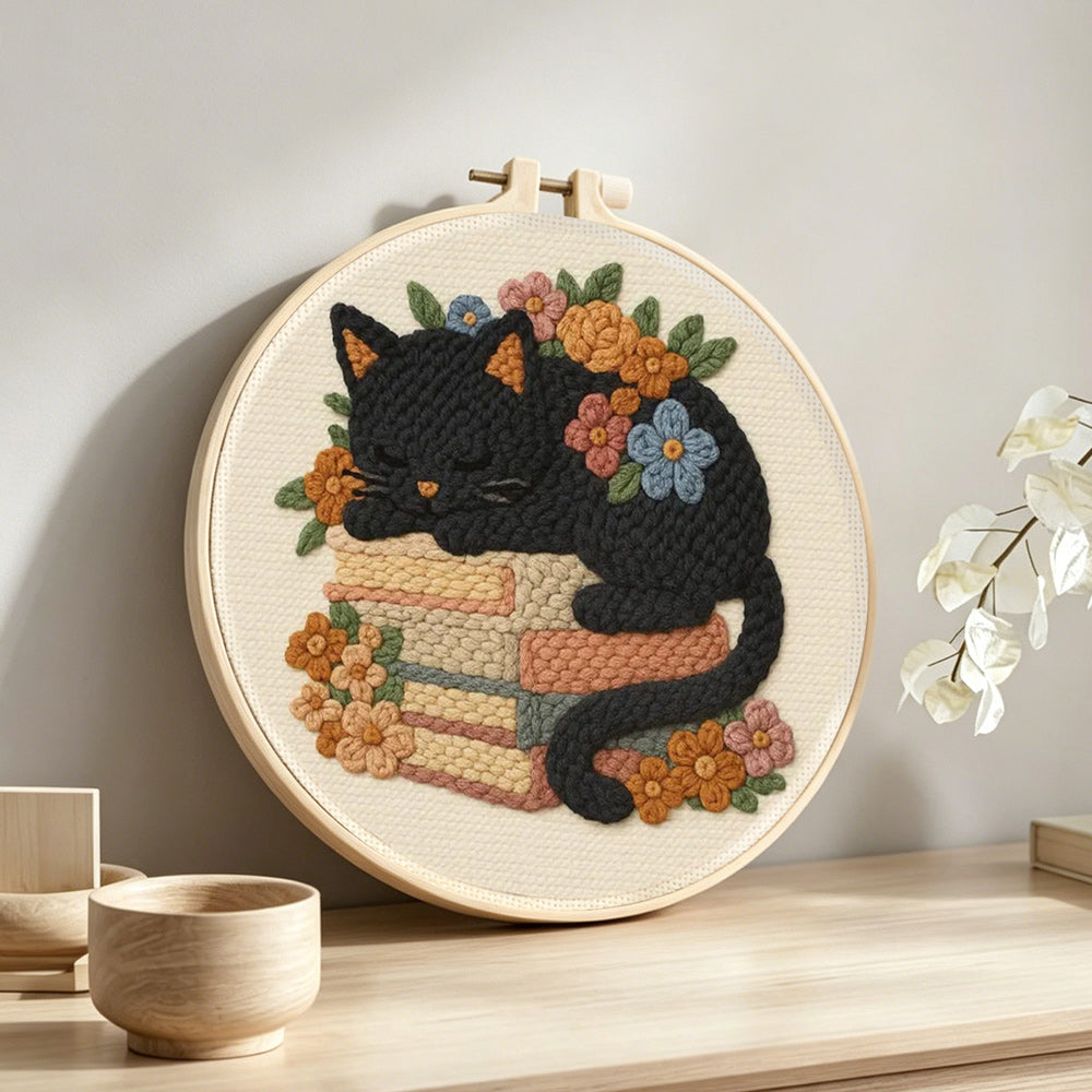 Cat sleeping on books punch needle artwork displayed on a table