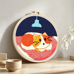 Cat under the chandelier punch needle artwork displayed on a table