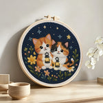 Cats and wildflowers under the night sky punch needle artwork displayed on a table