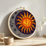 Celestial sunburst and crescent moon punch needle artwork displayed on a table
