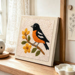 Charming bird on a flower branch punch needle artwork displayed on a table