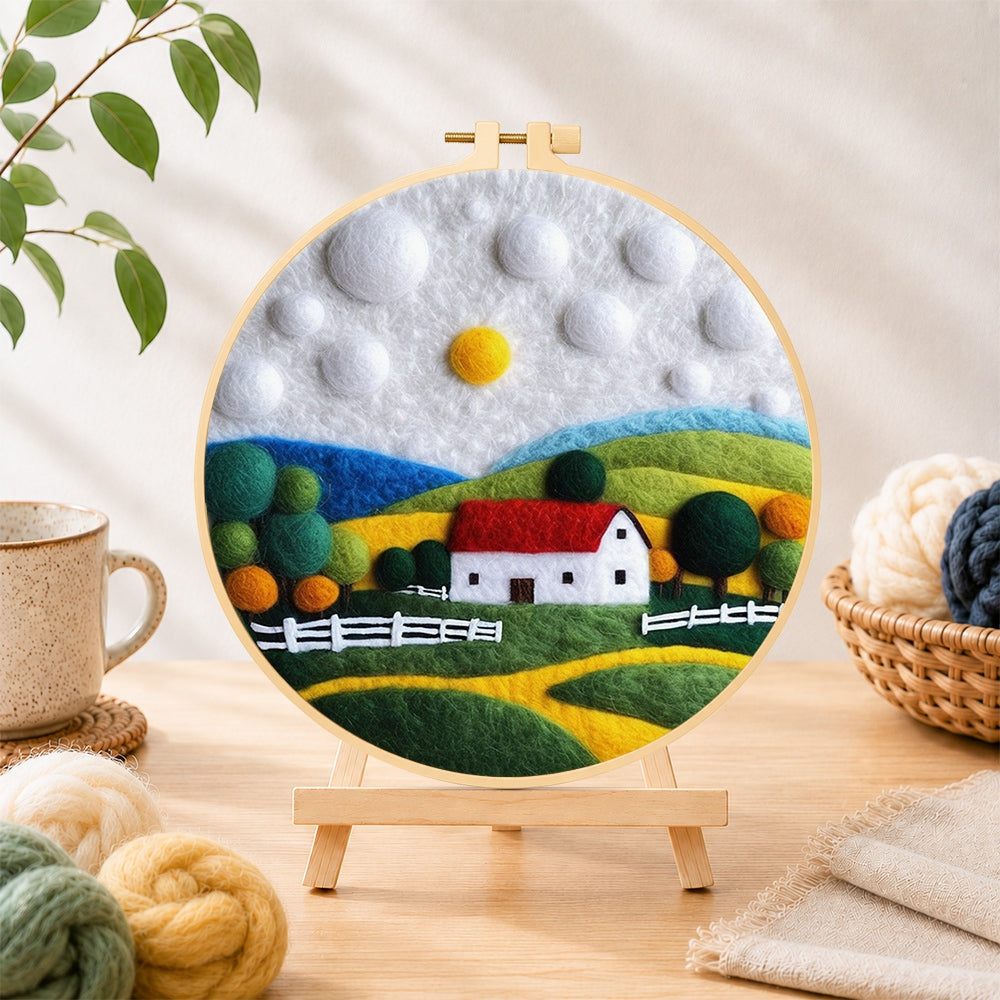 Finished charming red roof cottage needle felting displayed on a wooden easel