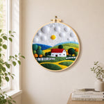 Charming red roof cottage needle felt wall art displayed in a bright home interior