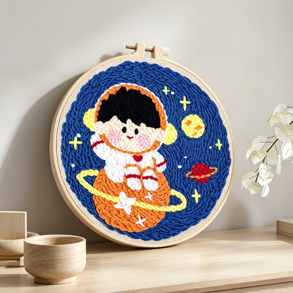 Charming space boy on orange planet punch needle artwork displayed on a table