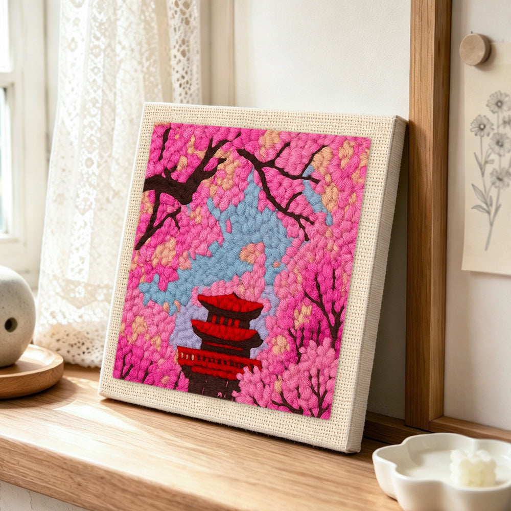 Cherry blossom and red pagoda punch needle artwork displayed on a table