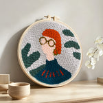 Chic boho lady with glasses punch needle artwork displayed on a table
