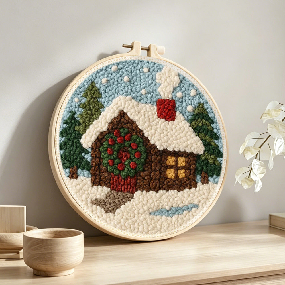 Christmas cabin with wreath and smoke punch needle artwork displayed on a table