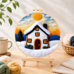 Finished christmas snowy cottage needle felting displayed on a wooden easel