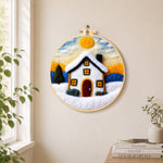 Christmas snowy cottage needle felt wall art displayed in a bright home interior