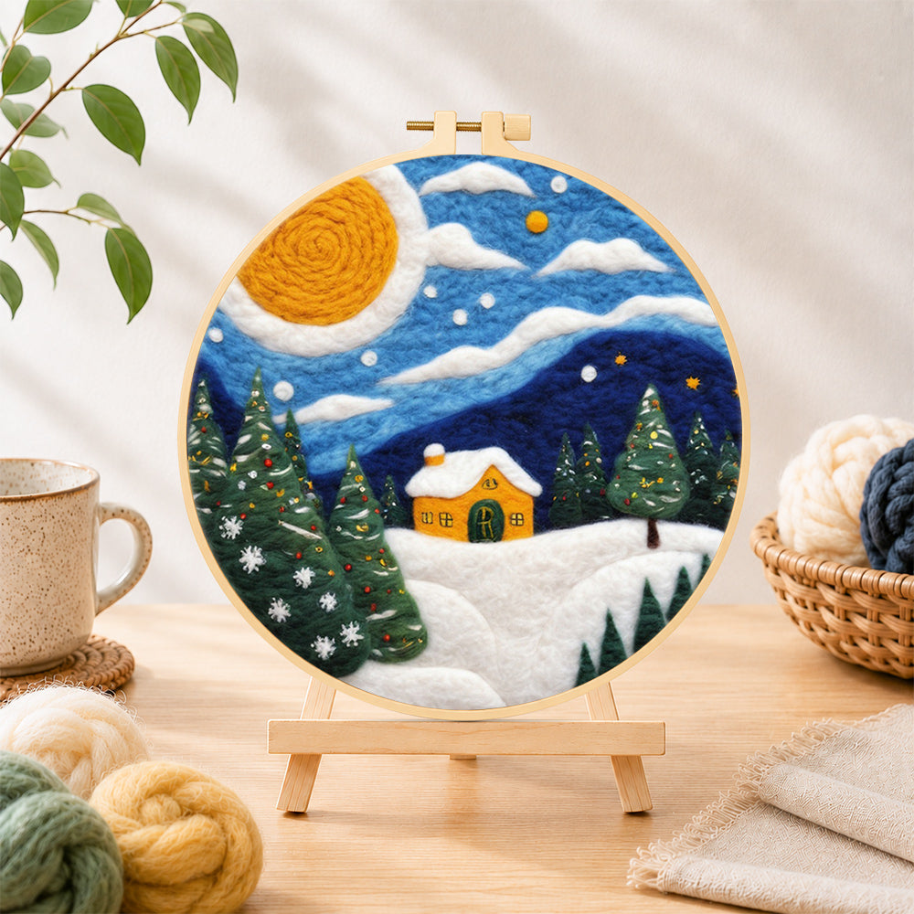 Finished christmas trees and a yellow cottage needle felting displayed on a wooden easel