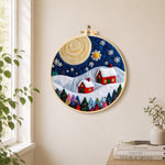 Christmas village with big moon needle felt wall art displayed in a bright home interior