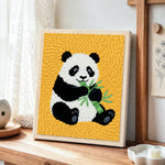 Classic panda eating bamboo punch needle artwork displayed on a table