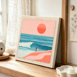Coastal surfer and peach sunset scene punch needle artwork displayed on a table