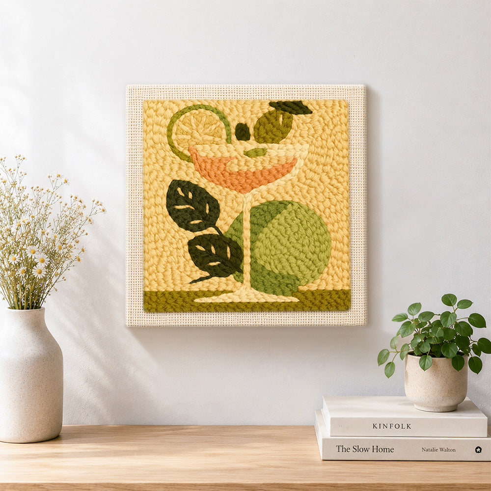 Finished cocktail with green leaves and lime artwork displayed on a wall
