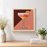 Finished cocktail with ice and orange slice artwork displayed on a wall