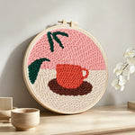 Coffee cup and leaf punch needle artwork displayed on a table