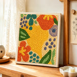 Colourful abstract botanical punch needle artwork displayed on a table
