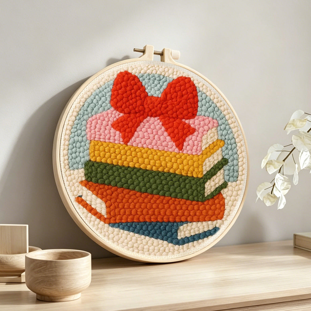 Colourful book stack with bow punch needle artwork displayed on a table