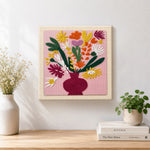 Finished colourful bouquet in burgundy vase artwork displayed on a wall