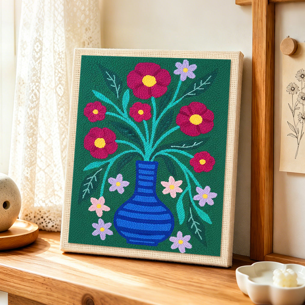 Colourful flowers in striped blue vase punch needle artwork displayed on a table