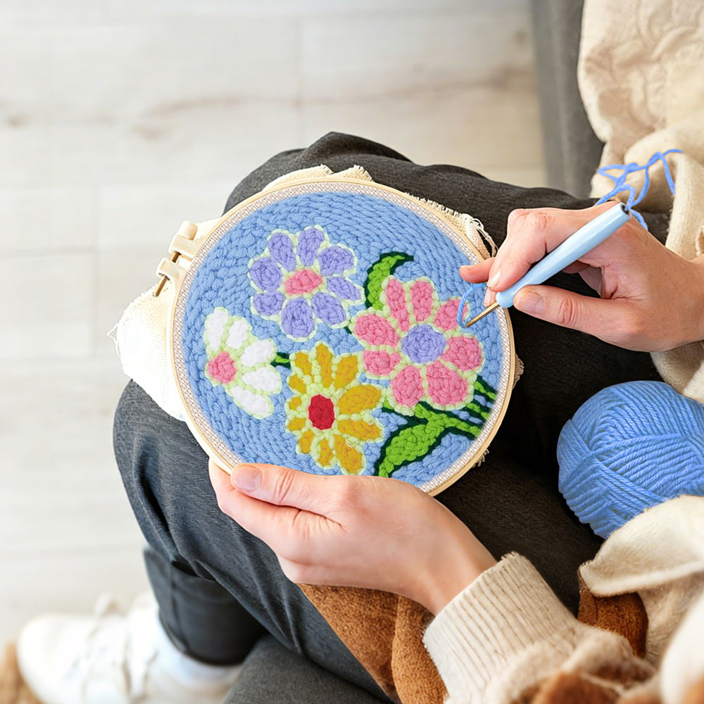 Creating handmade colourful flowers on blue background punch needle artwork