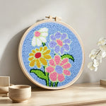 Colourful flowers on blue background punch needle artwork displayed on a table