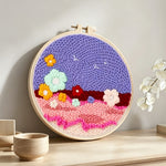 Colourful flowers on purple sky punch needle artwork displayed on a table
