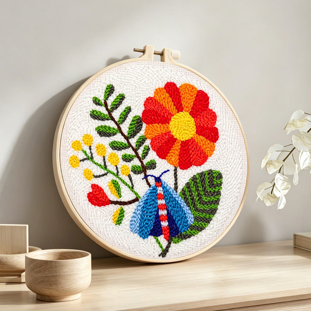 Colourful moth and large flower punch needle artwork displayed on a table