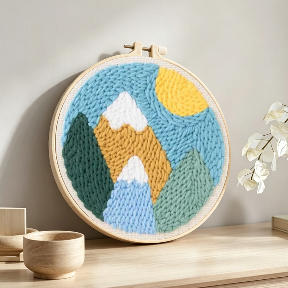 Colourful mountain landscape with sun punch needle artwork displayed on a table