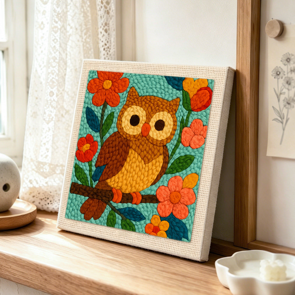 Colourful owl on flowering branch punch needle artwork displayed on a table