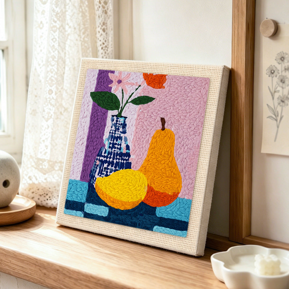 Colourful pear and vase still life punch needle artwork displayed on a table