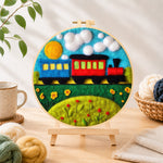 Finished colourful train on grass needle felting displayed on a wooden easel