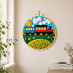 Colourful train on grass needle felt wall art displayed in a bright home interior