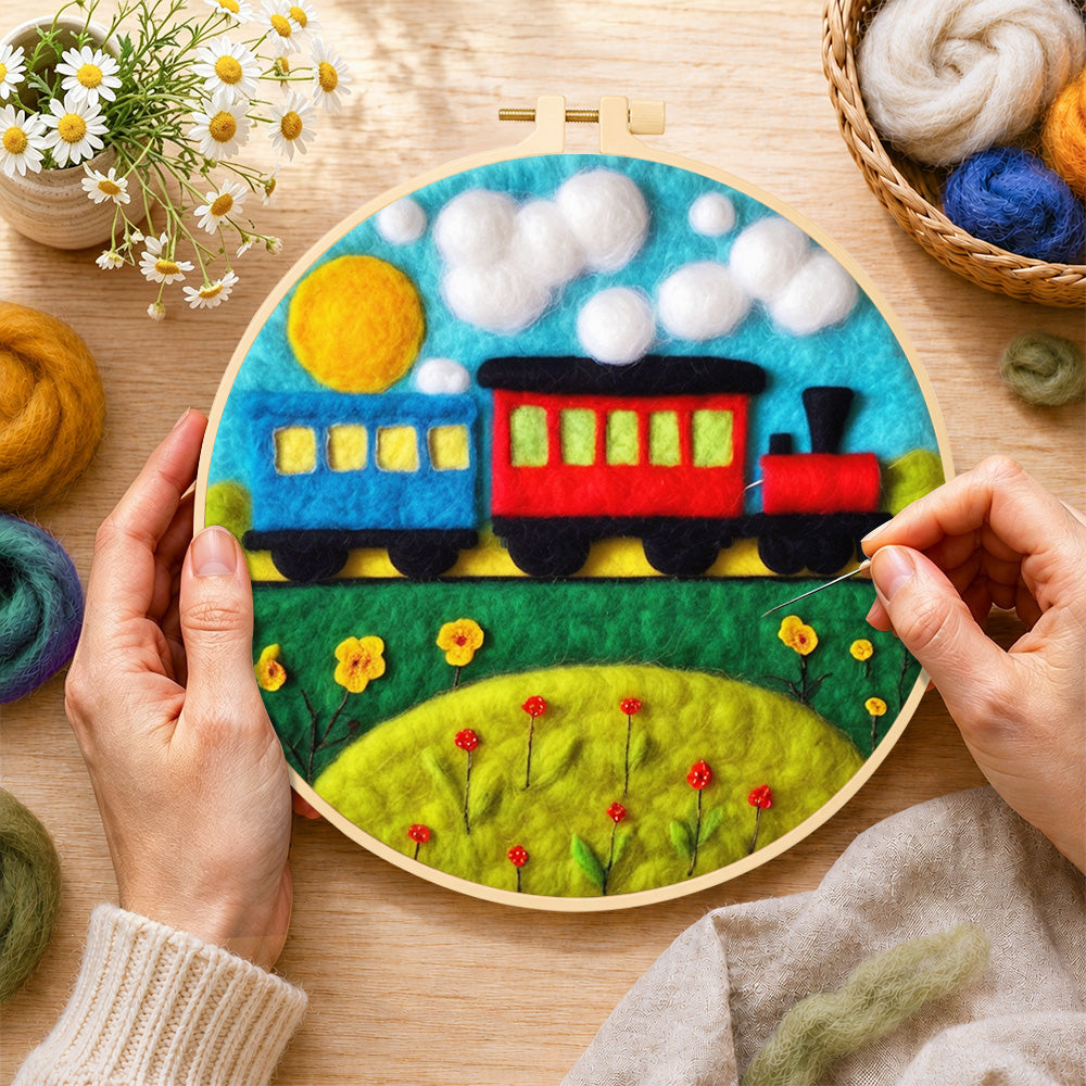 Creating the colourful train on grass wool painting by hand with a felting needle