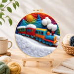 Finished colourful train on snowy hills needle felting displayed on a wooden easel