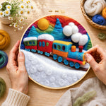 Creating the colourful train on snowy hills wool painting by hand with a felting needle